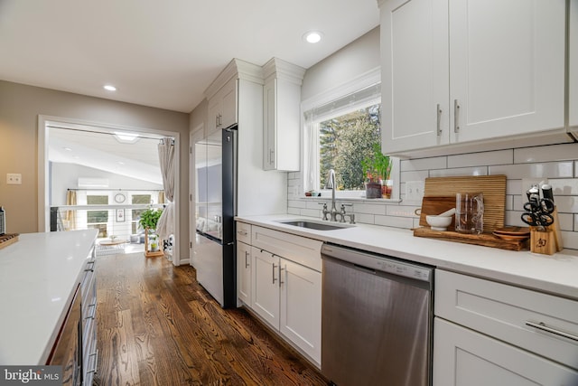 kitchen featuring sink, dark hardwood / wood-style floors, stainless steel appliances, white cabinets, and decorative backsplash