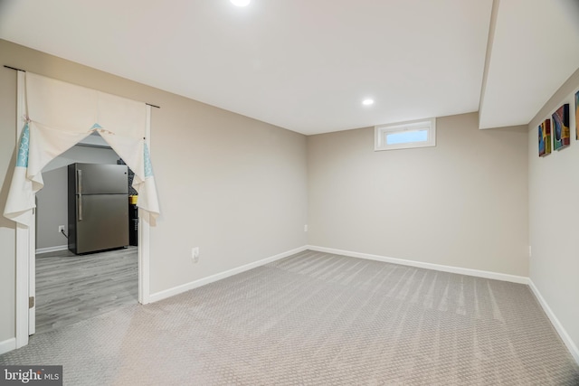 basement featuring light colored carpet and stainless steel fridge