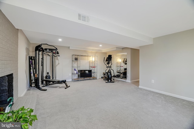 workout room with a tray ceiling, carpet floors, and a brick fireplace