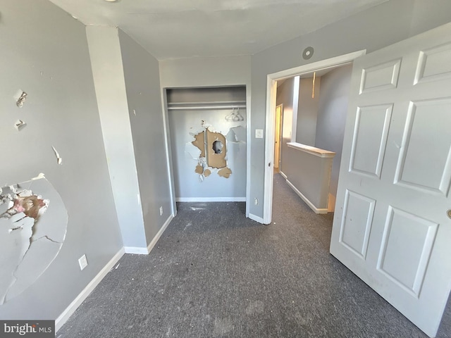 unfurnished bedroom featuring dark carpet and a closet