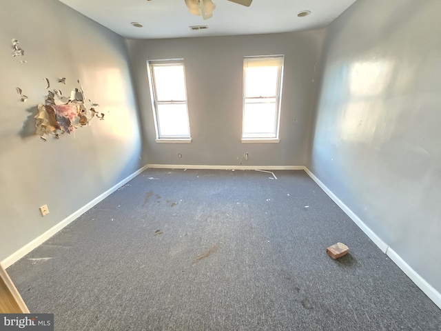 empty room with ceiling fan and dark colored carpet