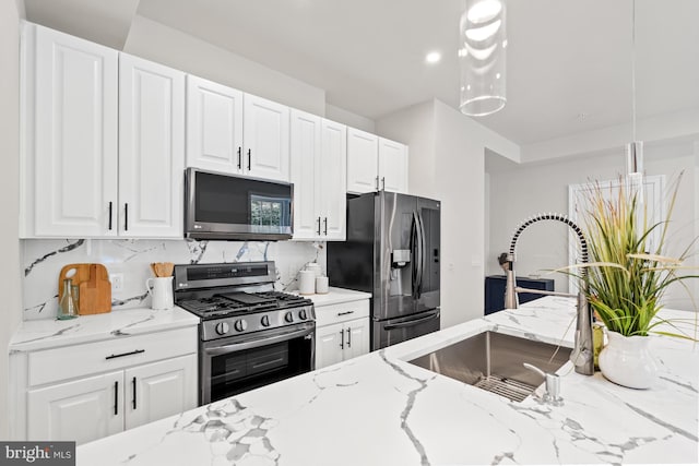 kitchen with stainless steel appliances, white cabinetry, light stone countertops, and sink