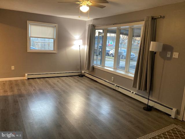 unfurnished room with ceiling fan, dark hardwood / wood-style flooring, and a baseboard radiator