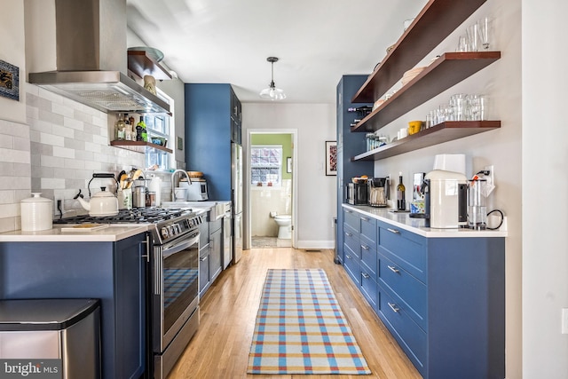 kitchen with open shelves, blue cabinetry, extractor fan, and stainless steel range with gas stovetop