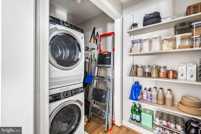 laundry room featuring laundry area, stacked washer and clothes dryer, and wood finished floors