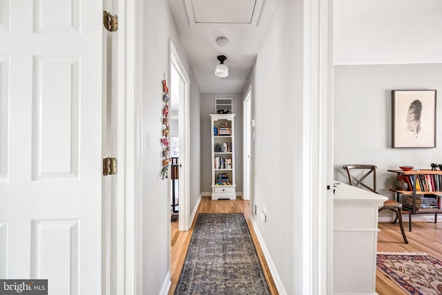 hallway featuring light wood finished floors and baseboards