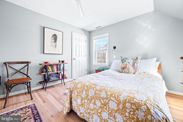 bedroom featuring lofted ceiling, baseboards, visible vents, and wood finished floors