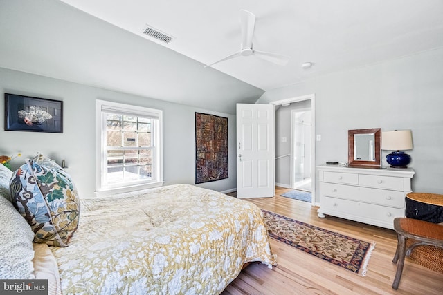 bedroom with a ceiling fan, lofted ceiling, visible vents, and wood finished floors