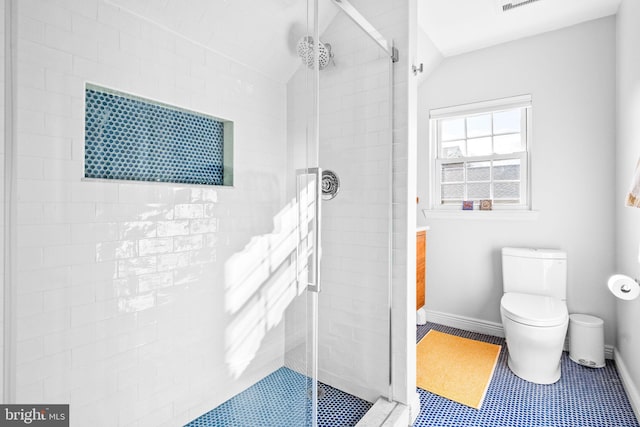 bathroom featuring a stall shower, toilet, and baseboards