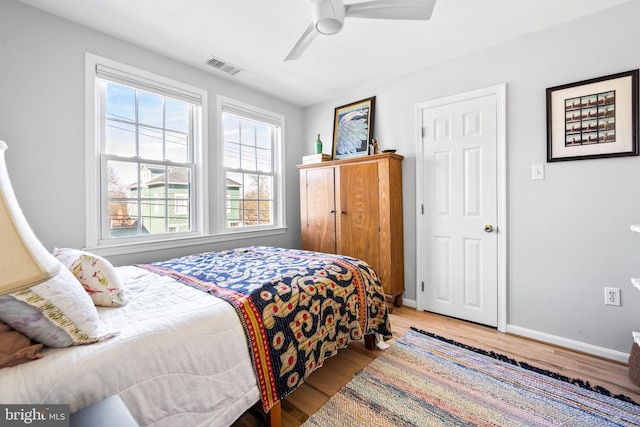 bedroom with ceiling fan, wood finished floors, visible vents, and baseboards