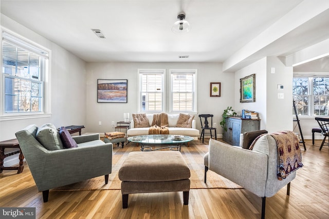 living room featuring a wealth of natural light, visible vents, and wood finished floors