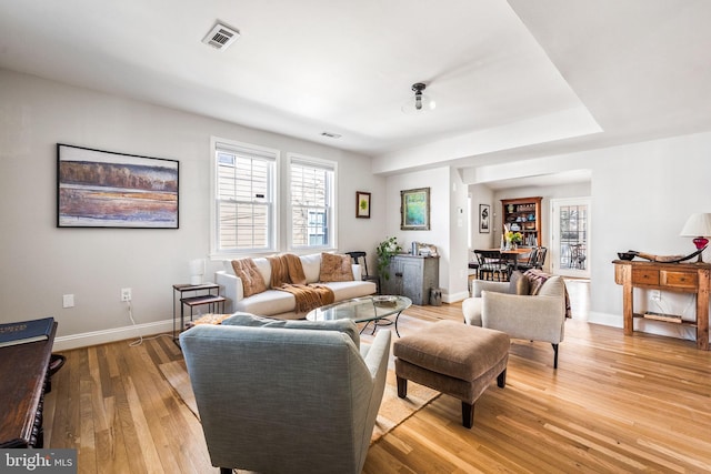 living room with visible vents, light wood-style flooring, and baseboards