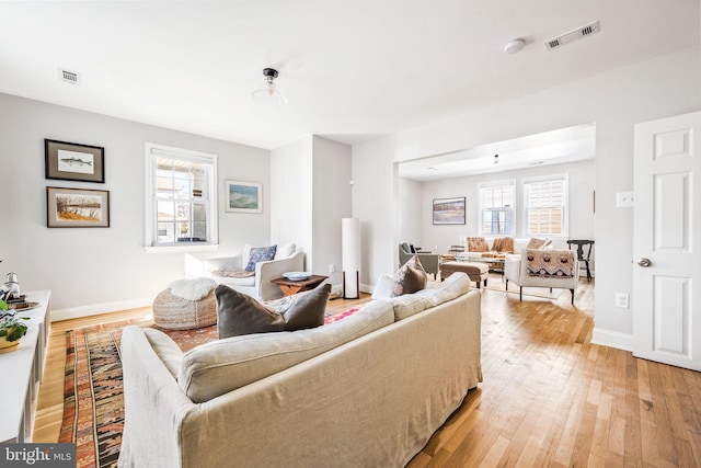 living area featuring light wood-type flooring, a healthy amount of sunlight, and visible vents