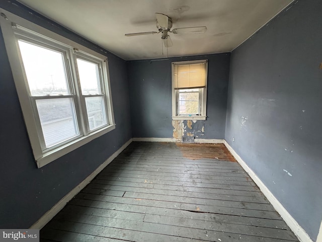 empty room featuring a ceiling fan, baseboards, and wood finished floors