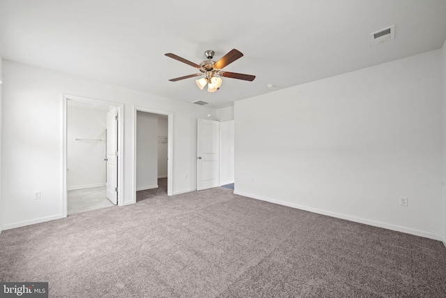 unfurnished bedroom featuring a walk in closet, carpet flooring, ceiling fan, and a closet