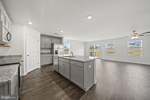 kitchen featuring dark wood-type flooring, sink, gray cabinetry, stainless steel appliances, and a kitchen island with sink