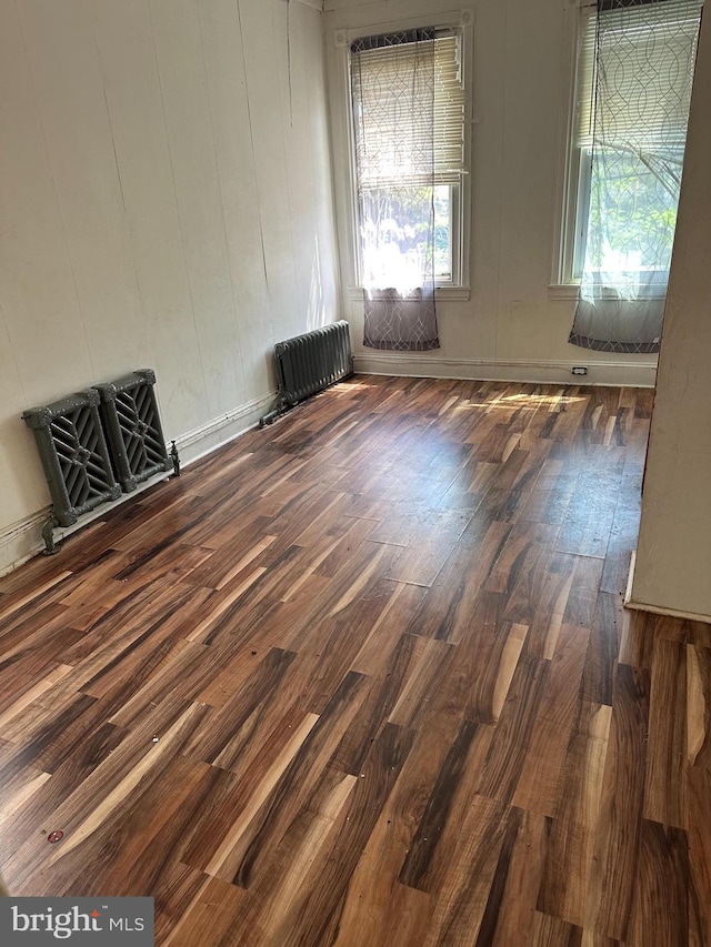 spare room with dark wood-style floors and radiator