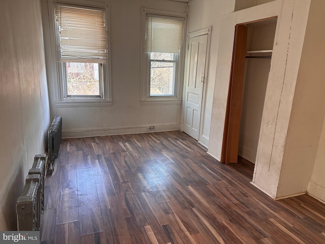 unfurnished bedroom with radiator heating unit and dark wood-style flooring