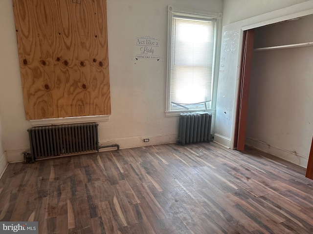 unfurnished bedroom featuring dark wood-style floors, multiple windows, and radiator