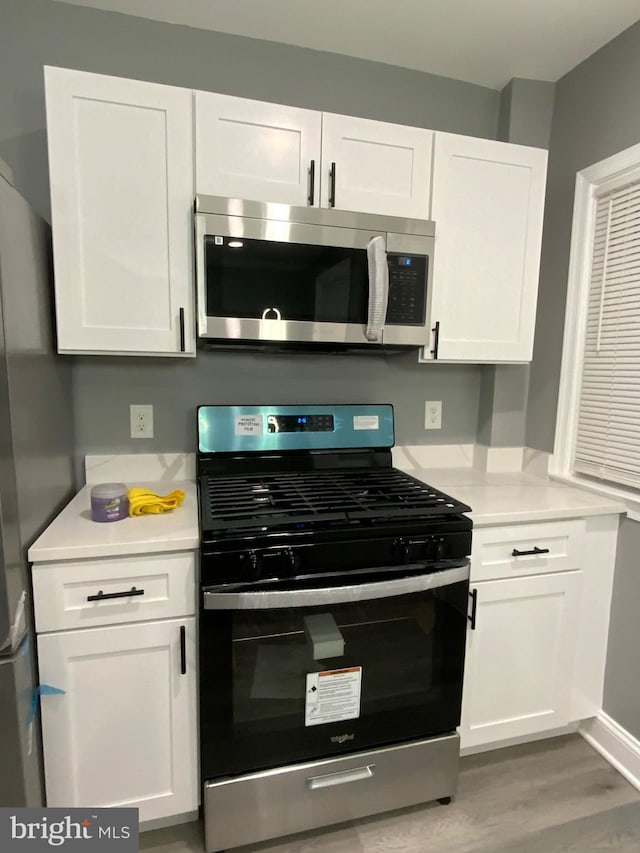 kitchen featuring white cabinetry, gas range oven, and light hardwood / wood-style flooring