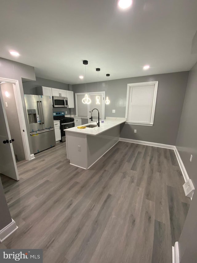 kitchen with pendant lighting, sink, white cabinetry, stainless steel appliances, and kitchen peninsula