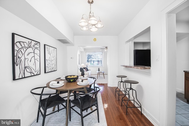 dining room with dark hardwood / wood-style floors and ceiling fan with notable chandelier