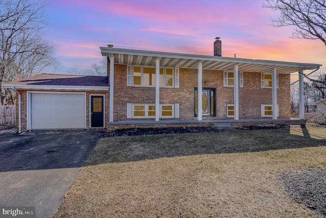 bi-level home featuring a porch, a garage, and a lawn