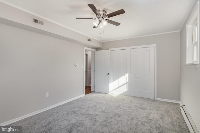 unfurnished bedroom featuring ceiling fan, baseboard heating, carpet, ornamental molding, and a closet