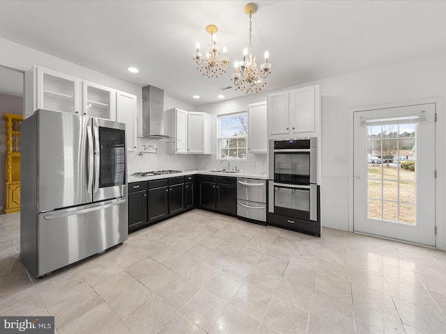 kitchen with glass insert cabinets, wall chimney range hood, white cabinetry, and stainless steel appliances