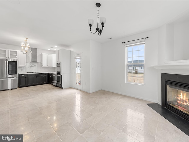 unfurnished living room featuring light tile patterned floors, recessed lighting, a notable chandelier, a fireplace with flush hearth, and baseboards