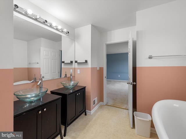 bathroom featuring a soaking tub, visible vents, vanity, and baseboards