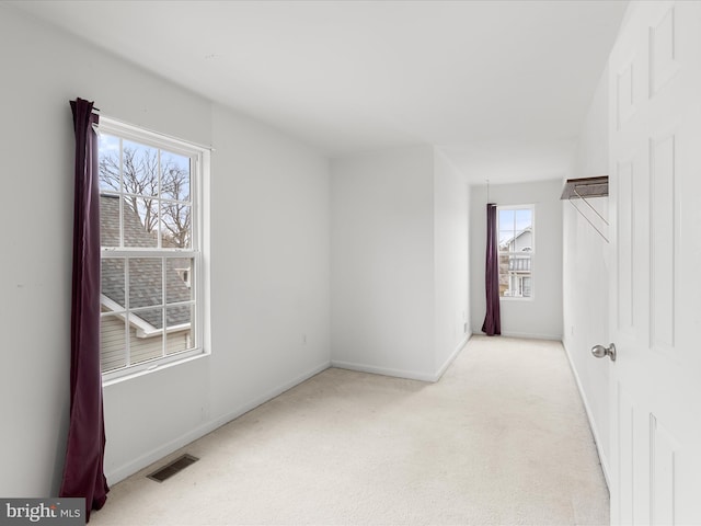 unfurnished room with visible vents, light carpet, and baseboards