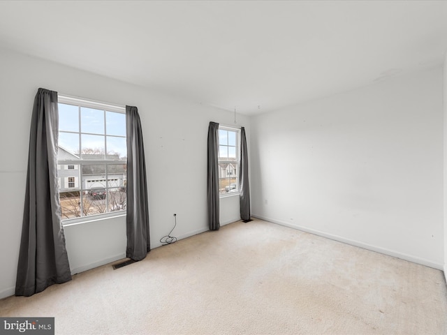 unfurnished room featuring light colored carpet, visible vents, and baseboards