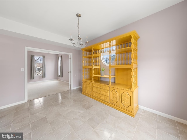 unfurnished dining area with a notable chandelier and baseboards