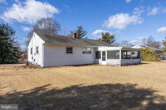 rear view of house featuring a sunroom, cooling unit, and a lawn