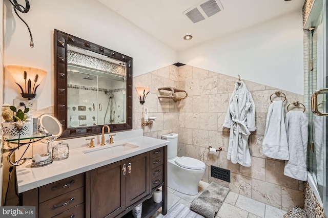 full bathroom featuring vanity, visible vents, a shower stall, tile walls, and toilet