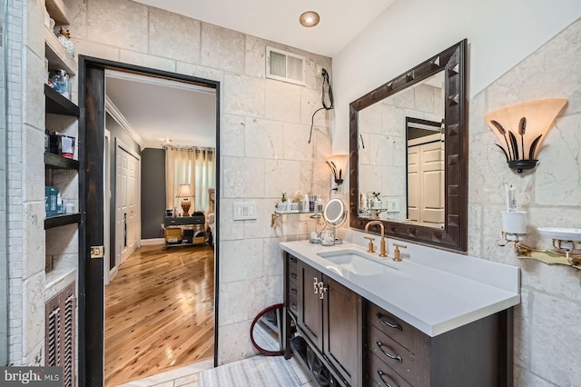 bathroom with visible vents, tile walls, wood finished floors, and vanity