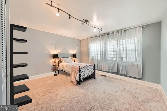 bedroom featuring visible vents, baseboards, track lighting, and carpet