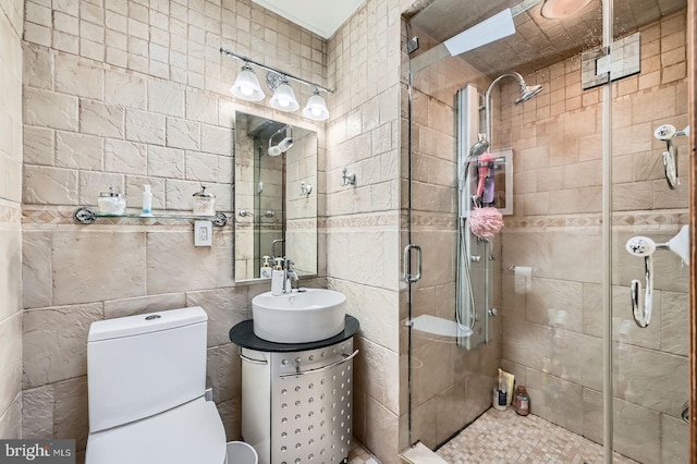 full bath with toilet, tile walls, a stall shower, and vanity