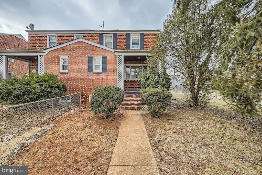 view of front facade featuring brick siding and fence