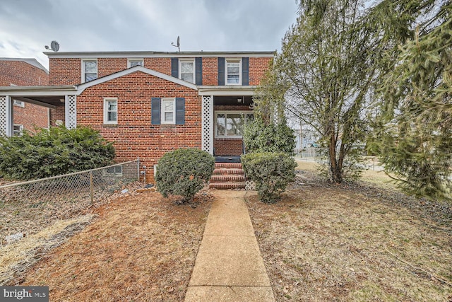 view of front facade featuring brick siding and fence