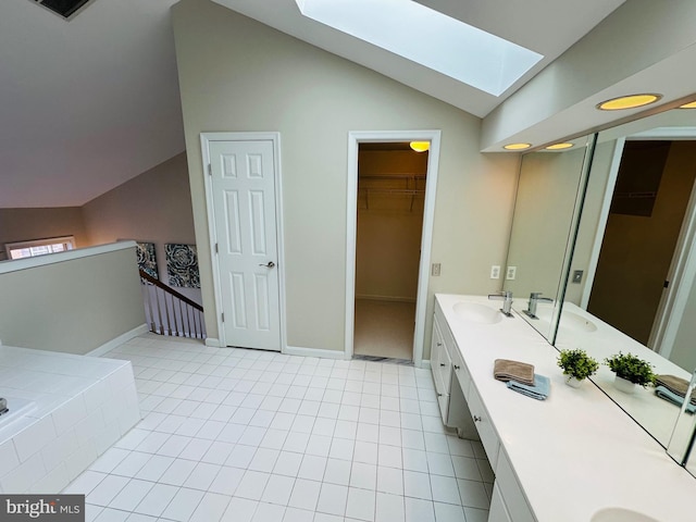 full bathroom featuring double vanity, lofted ceiling with skylight, a walk in closet, and a sink