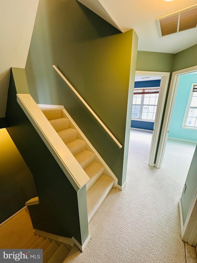 stairway with baseboards, visible vents, and carpet flooring