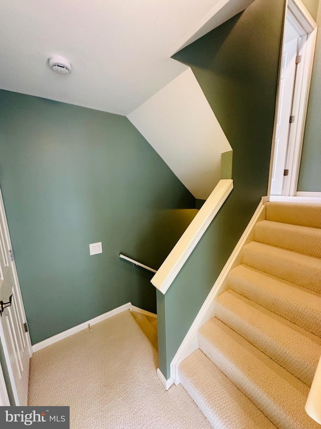 staircase featuring lofted ceiling, carpet, and baseboards