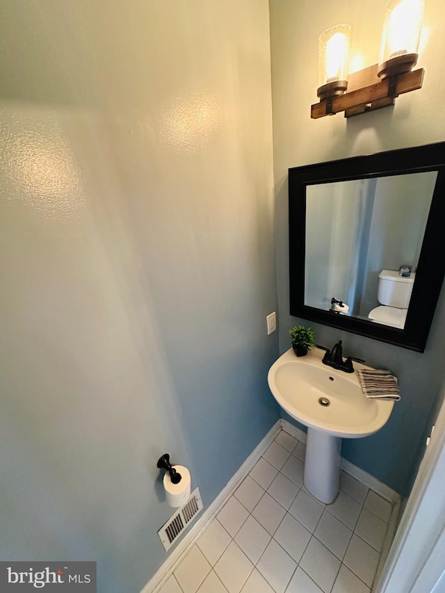 half bathroom featuring visible vents, toilet, a sink, tile patterned flooring, and baseboards