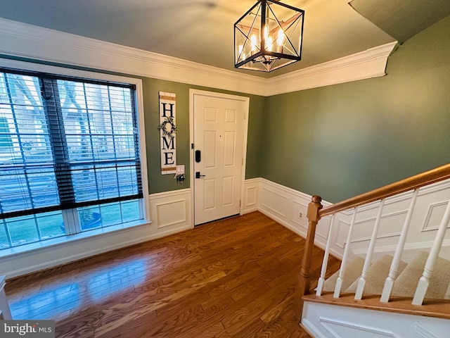 entryway with dark wood-style floors, crown molding, an inviting chandelier, and stairs