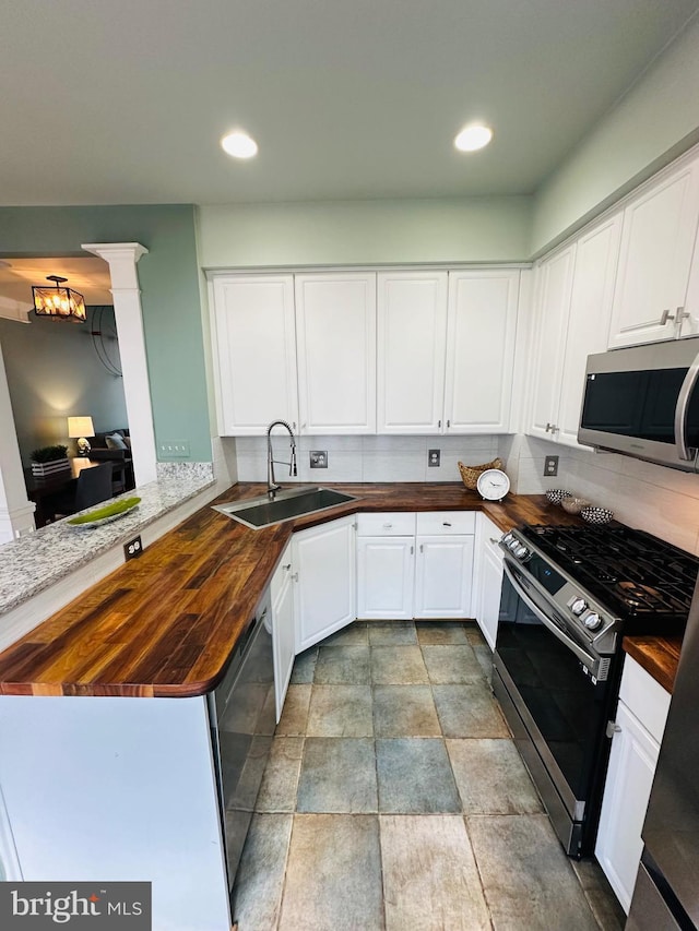 kitchen featuring appliances with stainless steel finishes, butcher block counters, white cabinets, and a sink