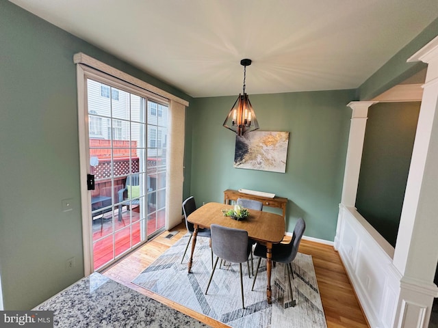 dining room featuring baseboards, wood finished floors, visible vents, and ornate columns