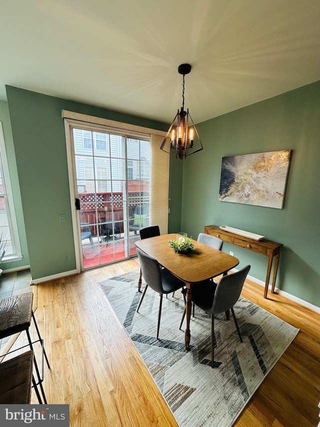 dining room featuring a notable chandelier, baseboards, and wood finished floors