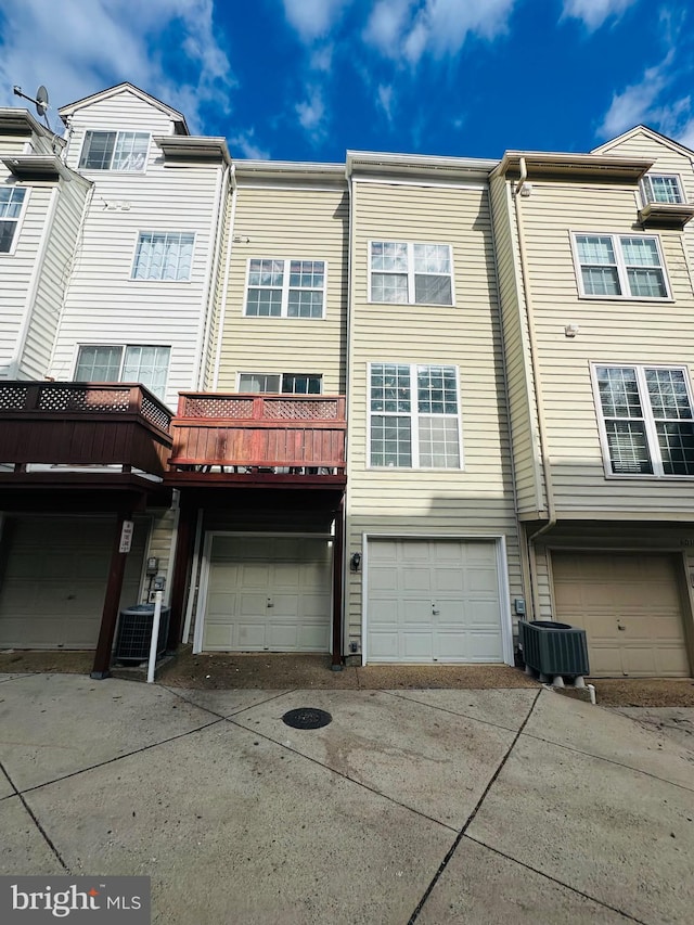 back of property with an attached garage and central air condition unit